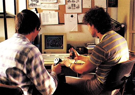 Zwei Personen vor einem Computer mit Joysticks