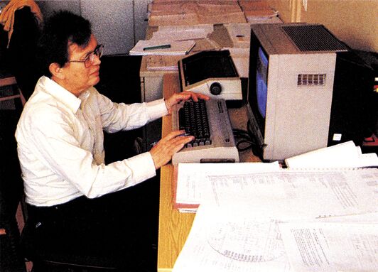 Person am C 64 mit Ausdrucken auf dem Schreibtisch