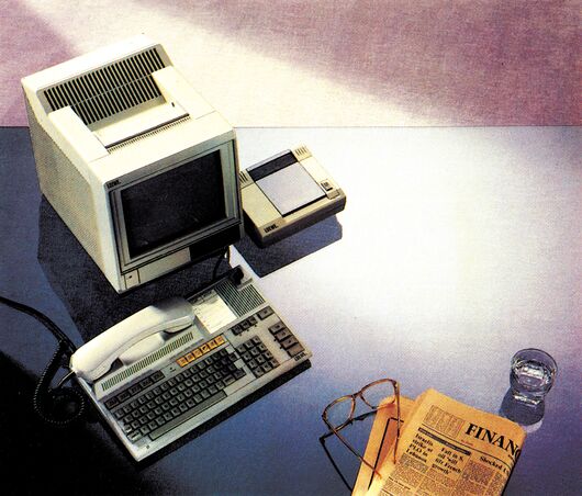 Produktfoto eines Btx-Terminals mit Bildschirm, Tastatur und Telefonhörer, daneben eine Brille und eine Zeitung