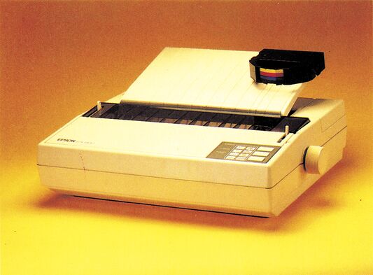 Freistehender cremefarbener Matrixdrucker mit eingesetzter Farbbandkassette und Bedienfeld, auf orangefarbenem Hintergrund