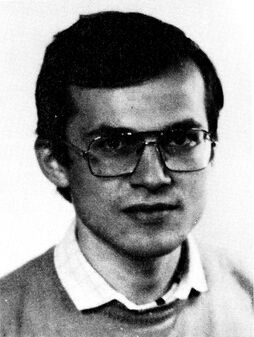 Porträtaufnahme eines Mannes mit Brille und kurzen Haaren, der in die Kamera blickt