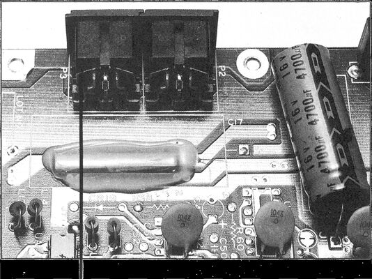 Foto einer Floppy-Platine mit zwei schwarzen Steckverbindern (P3, P2), Elektrolytkondensatoren und Bauteilen; ein Zeiger weist auf einen Kontakt