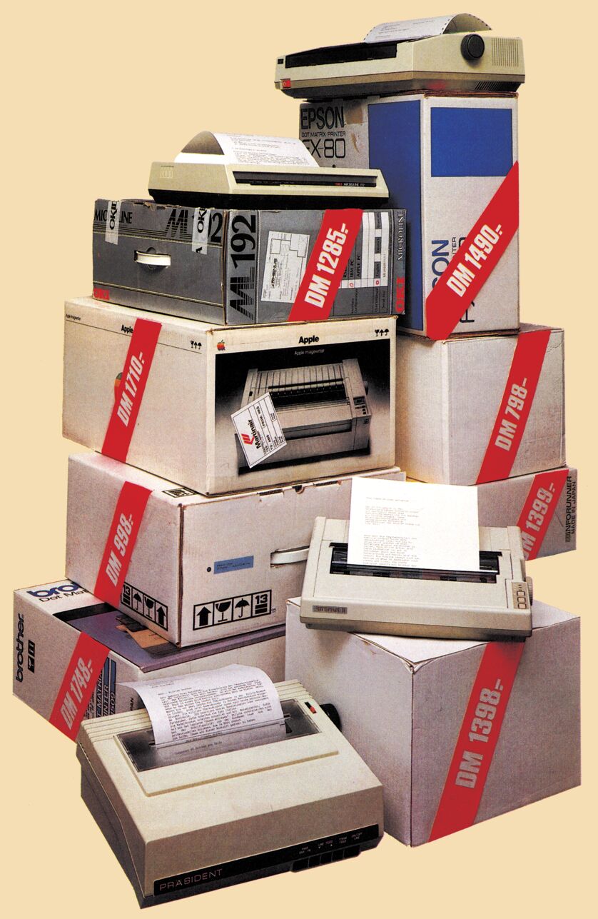 Stapel von Druckerkartons mit roten Preisschildern und mehrere Matrixdrucker mit Papierausdrucken