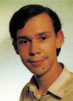 Porträtfoto einer Person mit dunklen Haaren und kariertem Hemd