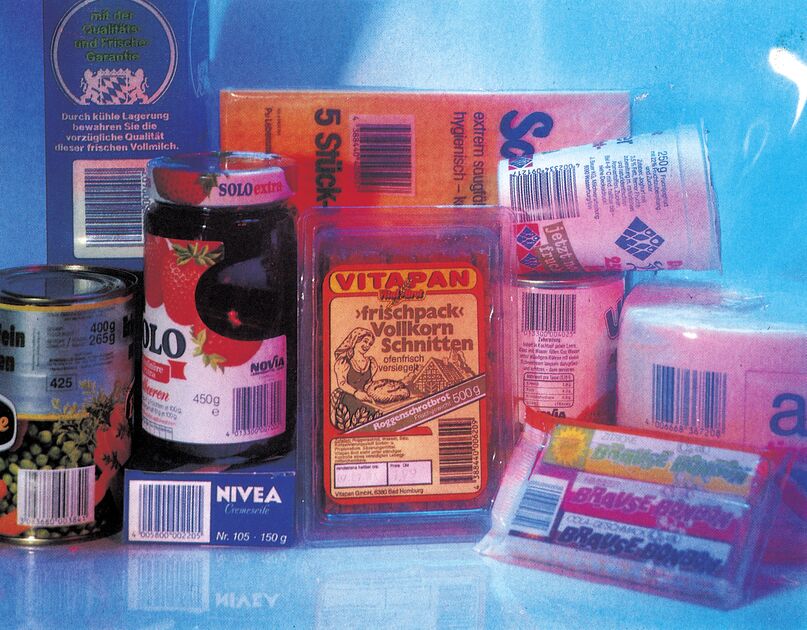 Lebensmittelverpackungen, Dose, Glas und Seife mit Strichcodes vor blauem Hintergrund