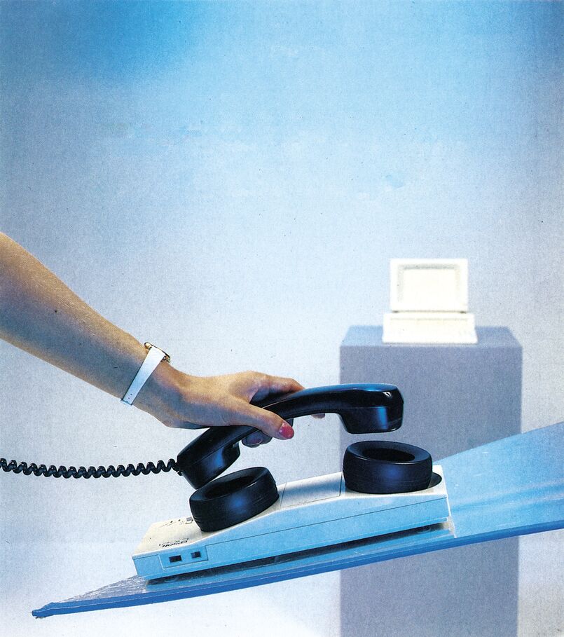 Farbfoto einer Hand, die einen Telefonhörer auf einen Akustikkoppler legt