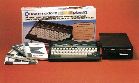 Commodore Plus/4 mit Verpackungskarton, Handbüchern und Datasette auf rotem Grund