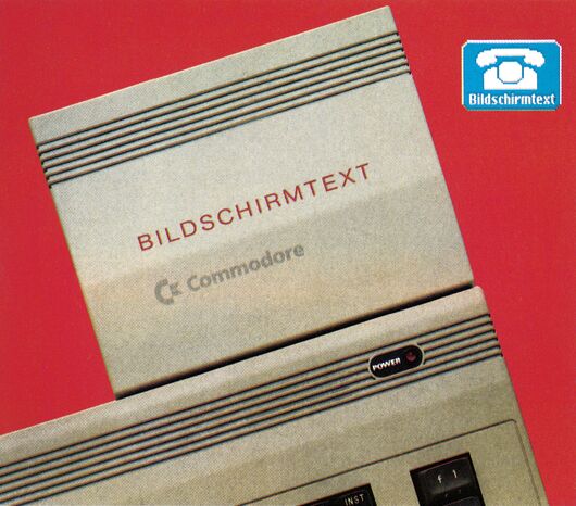 Helles Modul mit der Aufschrift »Bildschirmtext« und Commodore-Logo, eingesteckt in einen Computer, vor rotem Hintergrund mit Btx-Symbol