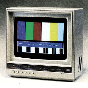 Farbmonitor Orion CCM-1280 im Dreiviertelprofil mit einer Reihe Drehknöpfe an der Front, auf dem Bildschirm ein Testbild mit Farbbalken