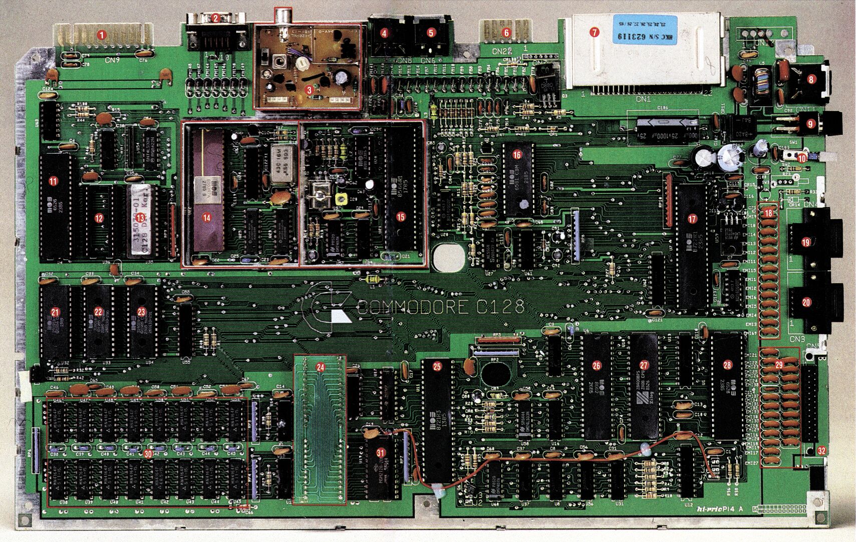 Farbfoto der ausgebauten Platine des C 128 mit Bauteilen und Anschlüssen; 32 rot umkreiste Ziffern markieren einzelne Bereiche