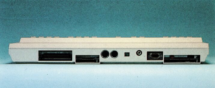 Farbfoto der Rückseite des C 128 mit Steckplatz, Anschlußöffnungen, zwei Rundbuchsen und einer neunpoligen Buchse