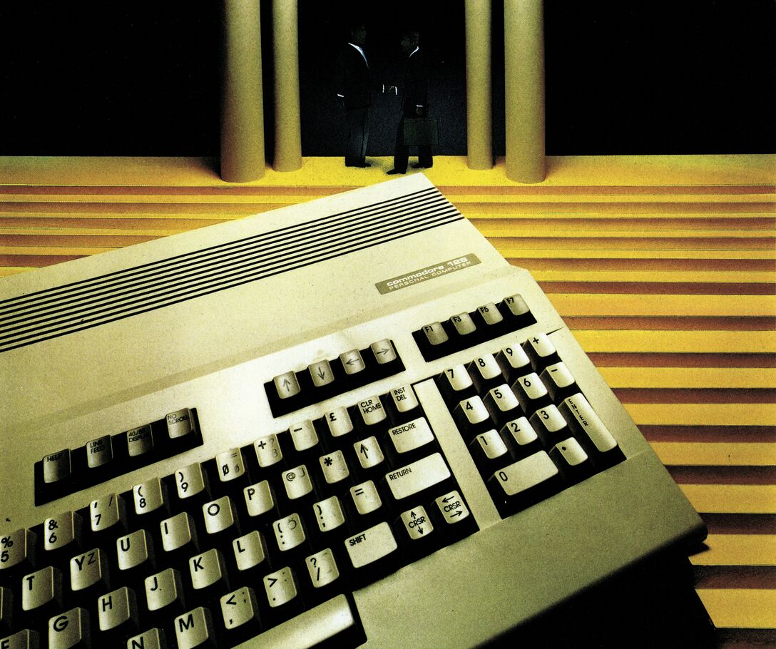 Farbfoto eines Commodore 128 mit integrierter Tastatur; dahinter eine breite Treppe mit Säulen und zwei stehenden Personen in Anzügen, eine davon mit Aktenkoffer